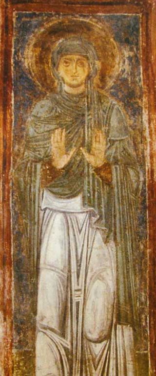 Byzantine fresco of Saint Macrina the Younger standing with both hands raised in the orans posture of prayer, wearing a dark veil and pale robe, with a gold halo.